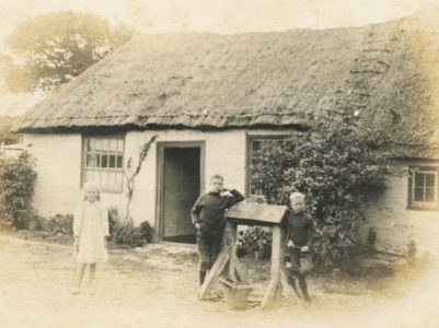 Selsey: Three children in front of a thatched building - thumbnail image